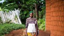 A woman poses for a photo outside of a home in Burundi.