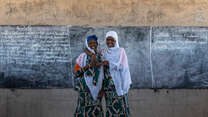 Two women stand together at the front of a classroom in Chad.