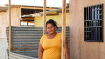 A woman stands outside her home in Peru and poses for a photo.