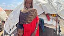 A mother stands next to her child outside their makeshift shelter in Somalia.