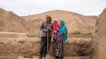 A family of three poses for a portrait in rural Afghanistan.