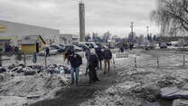 Refugees arrive at Medyka border crossing point, Poland. They are wearing warm clothing, around them, snow lies on the ground. 