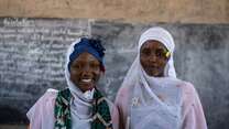 Two students stand at the front of a school in Chad and pose for a photo.