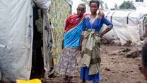 A son stands next to his mother at a camp for displaced people in the DRC.