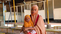 Damac sits with her daughter, Nimo, who is receiving EU-funded treatment for malnutrition, as they wait for a routine nutrition check-up in Health Post L, in Hagadera, Kenya.