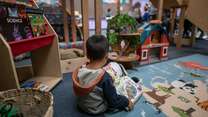 A young boy reads a book by himself at the IRC's Welcome Center in Phoenix, Arizona.