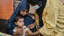 An IRC health care worker screens a young Rohingya child for signs of malnutrition.
