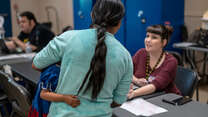 A woman and child seeking asylum in the U.S. speak with an IRC representative in an Arizona welcome center