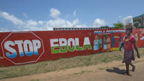 A woman in Monrovia, Liberia, walks past a mural that reads "Stop Ebola." 