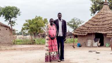 A man and woman embrace while posing for a photo outside their home in South Sudan.