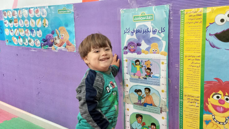 Saeed stands next to a poster during an Ahlan Simsim program.