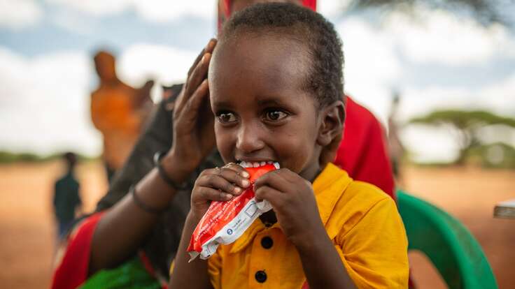 A young boy eats a peanut-based therapeutic food provided by the IRC in Somalia.