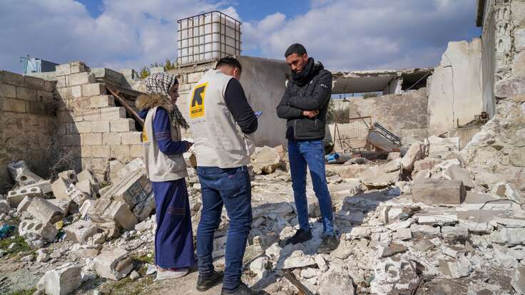 An IRC speaks with a client in the remains of a home destroyed by a severe earthquake in Syria.