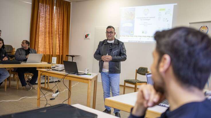 Ein Mann hält eine Präsentation vor einer Gruppe von Menschen in einem Seminarraum