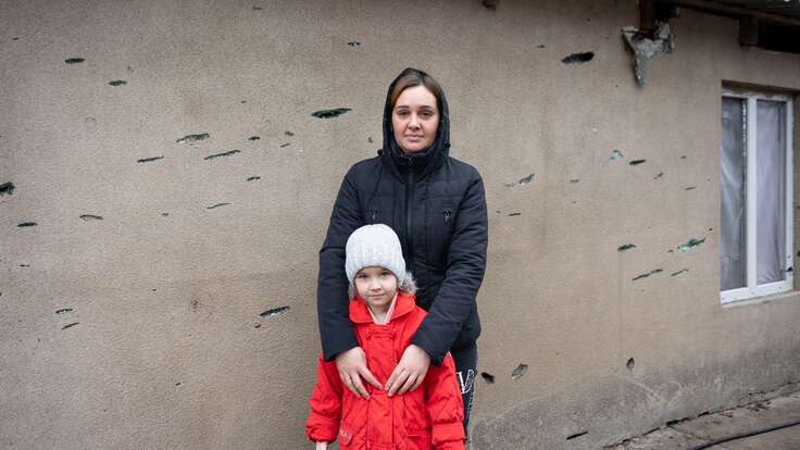 A mother and daughter stand outside of their home in Kherson, damaged by the war in Ukraine.